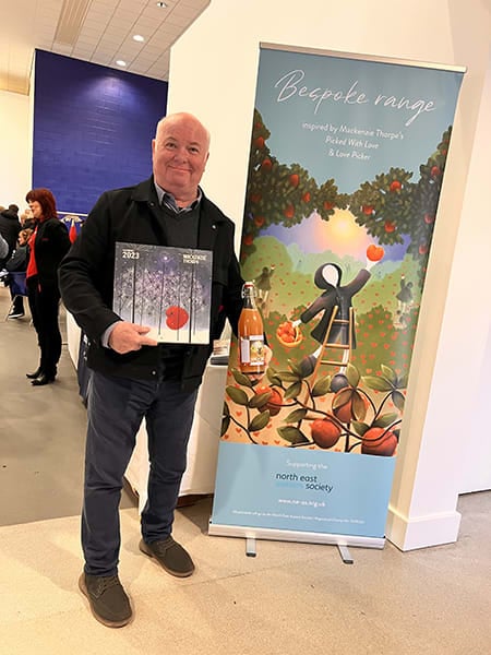 Artist standing next to a poster of his work