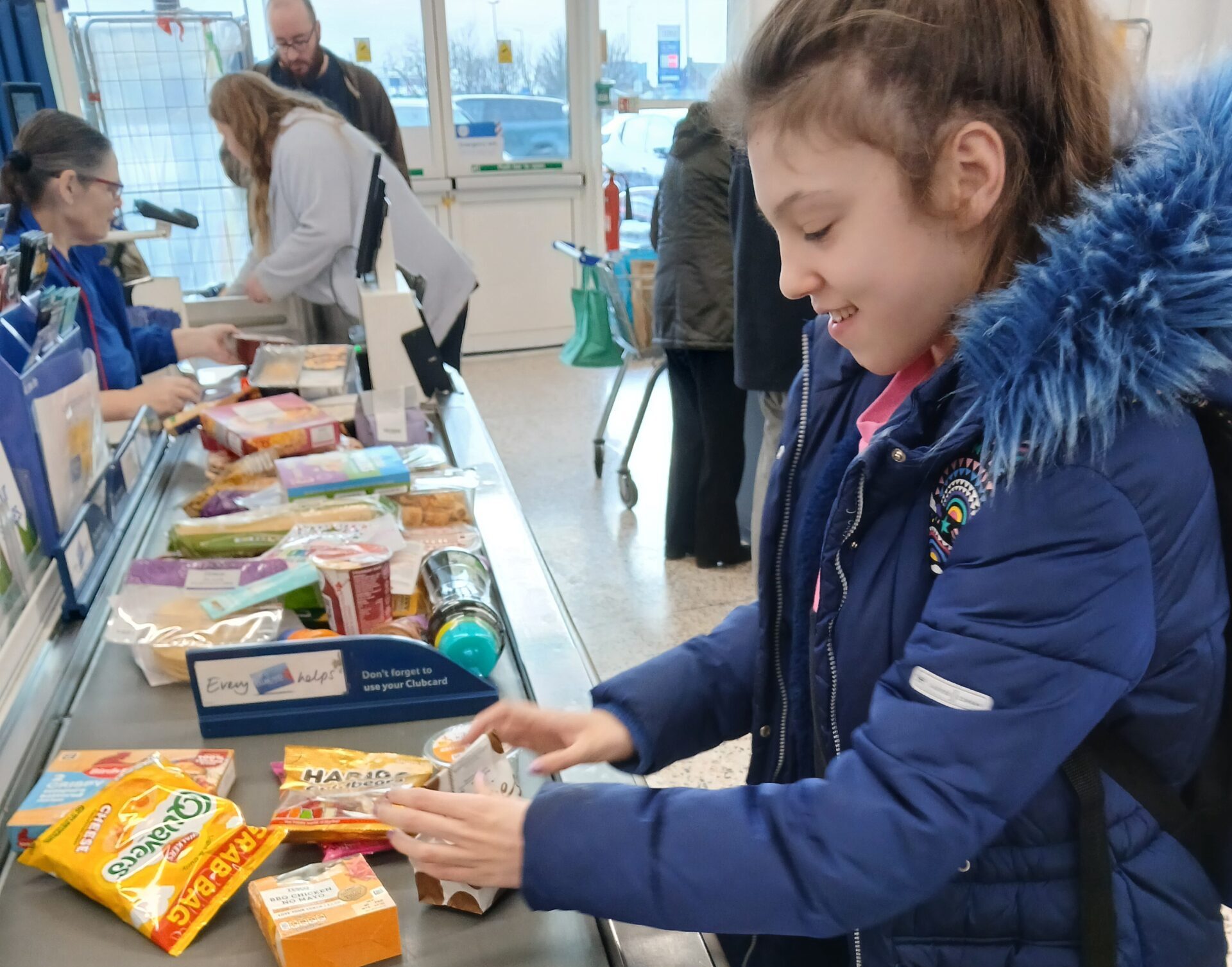 A girl puts food through a supermarket checkout