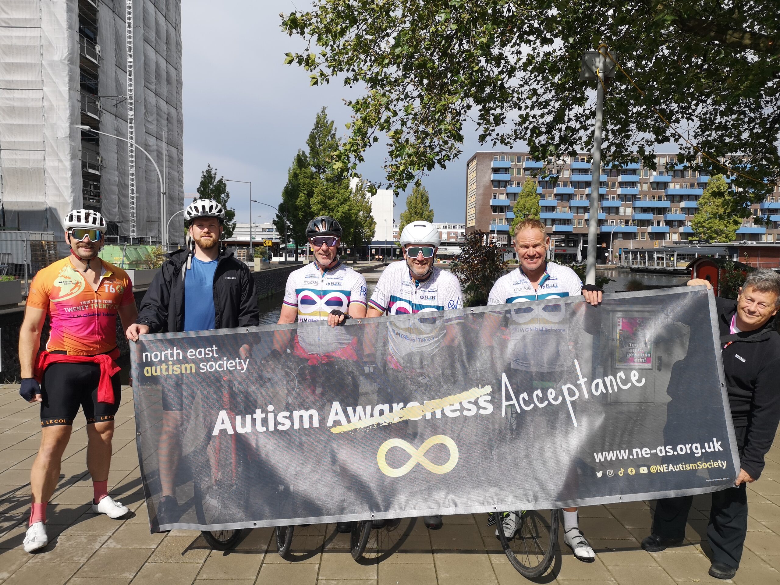 Cyclists holding up an Autism Acceptance banner