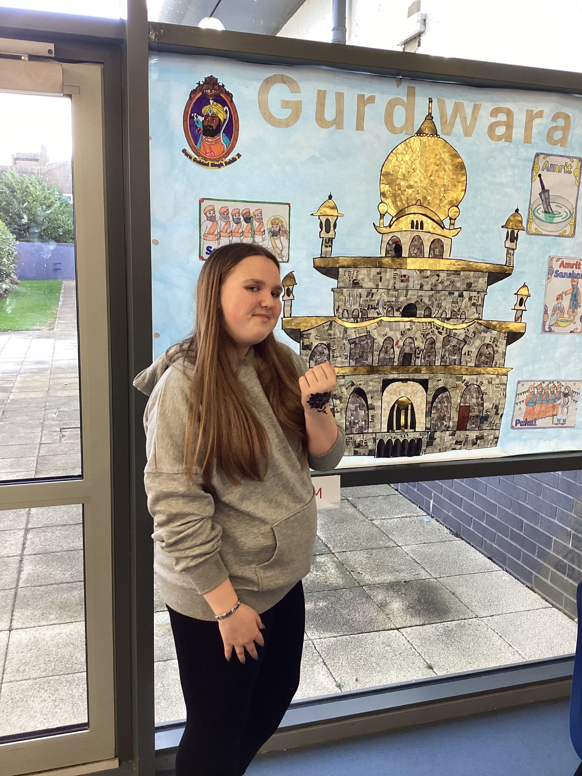 A girl standing next to a Sikh poster