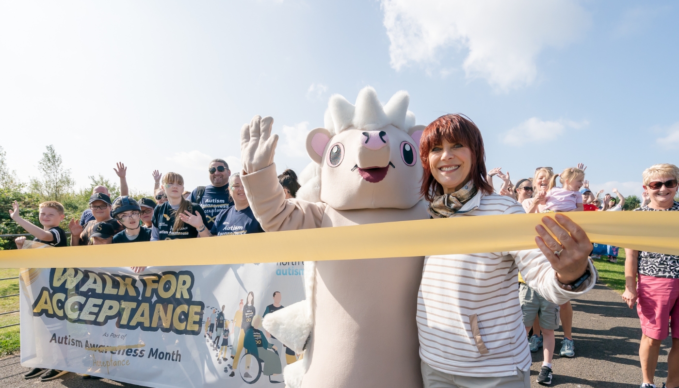 NEAS patron Pam Royle stands with mascot Snowdrop at the Walk for Acceptance starting line.